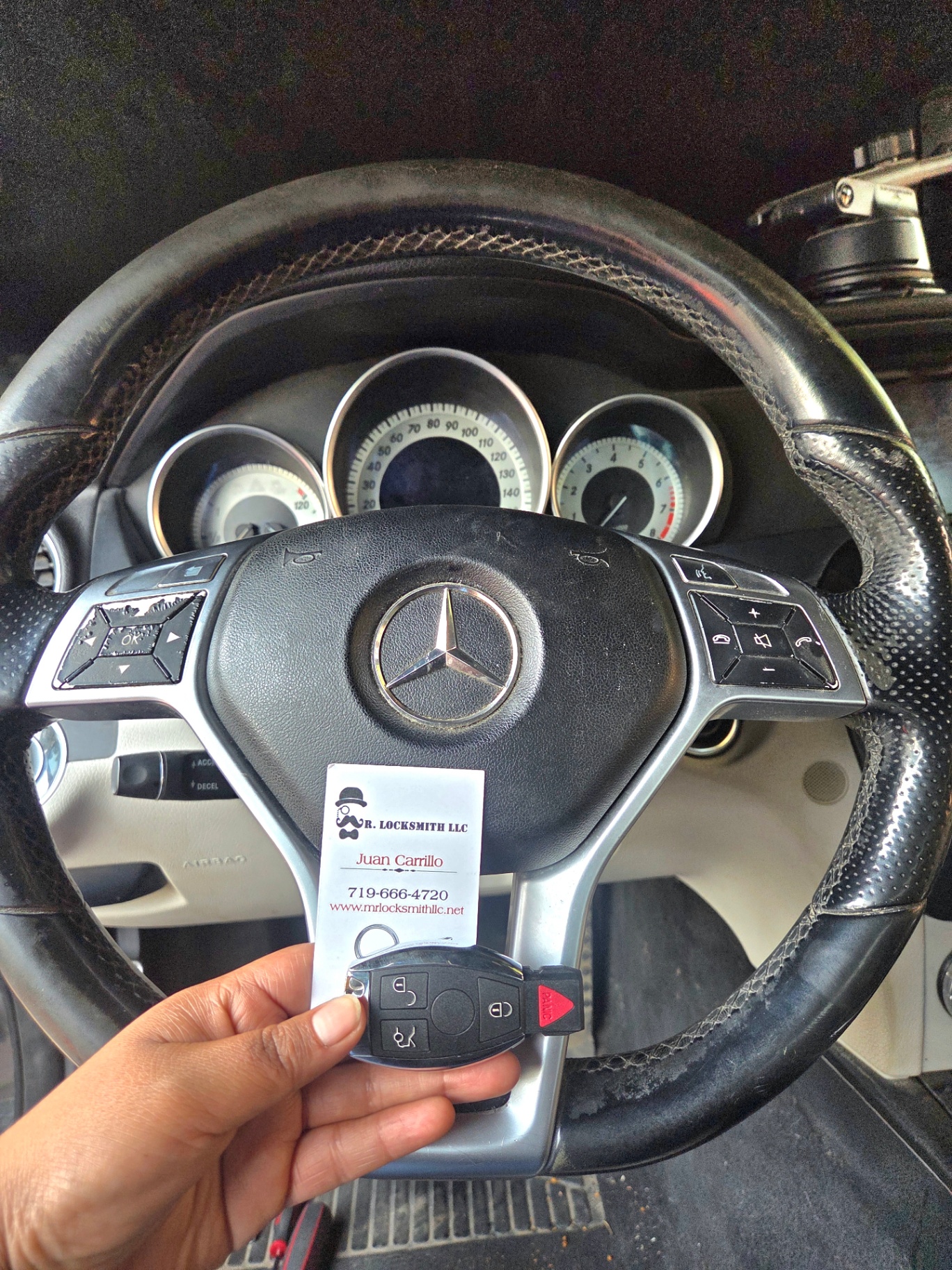 New Mercedes-Benz C300 smart key made on-site — held in front of the steering wheel with Mr. Locksmith business card